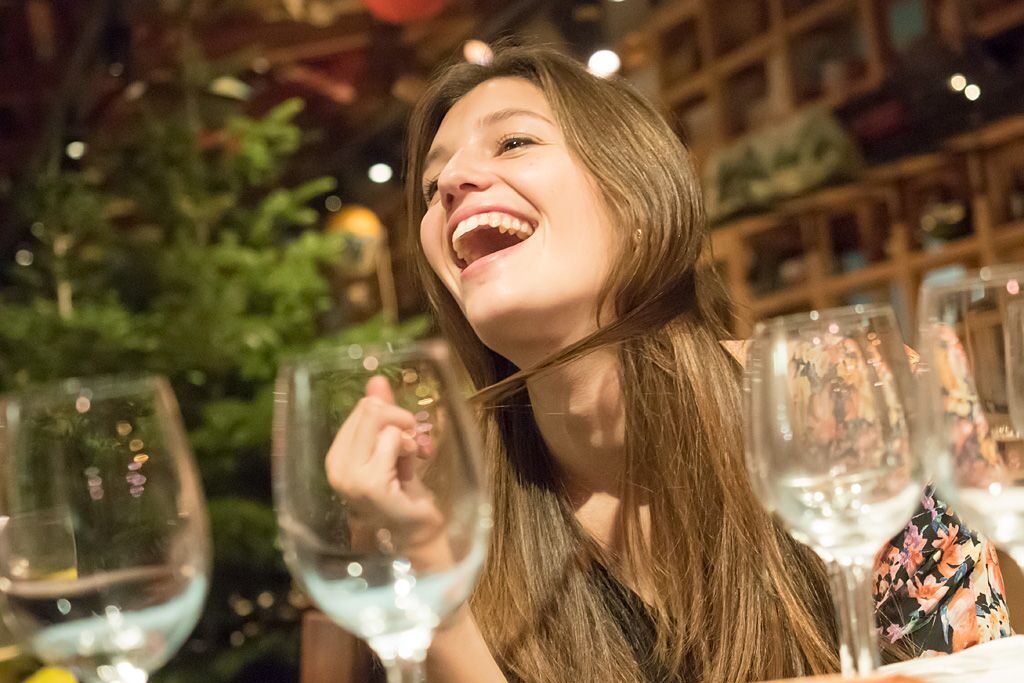 Mujer riendo durante un afterwork de Canela PR, con copas y ambiente distendido en un evento corporativo.