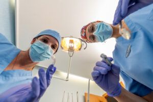 Dos profesionales sanitarias mirando hacia el paciente durante una sesión fotográfica para web de clínica.