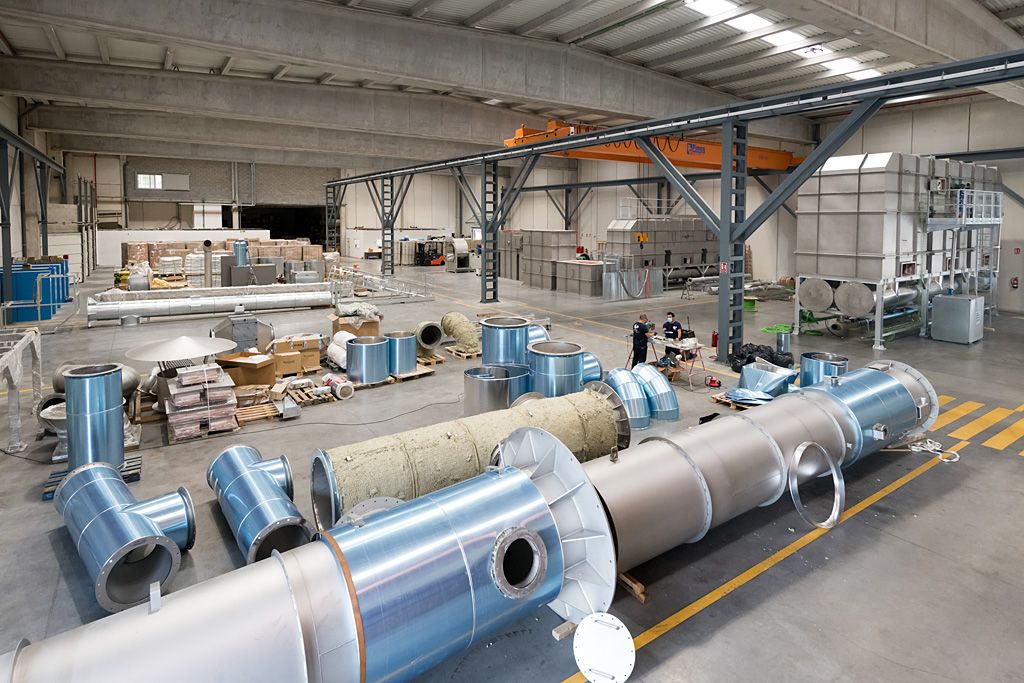 Vista general del interior de una planta industrial con grandes conductos y equipos metálicos distribuidos por la nave.