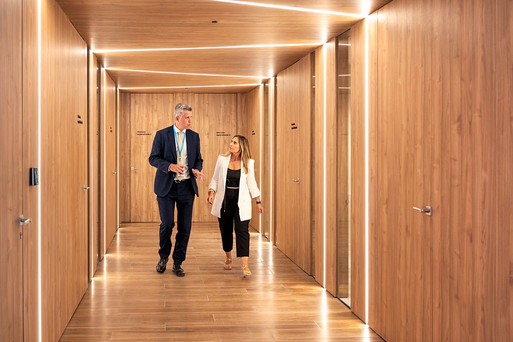 Dos personas caminando y conversando en un espacio corporativo de oficinas.