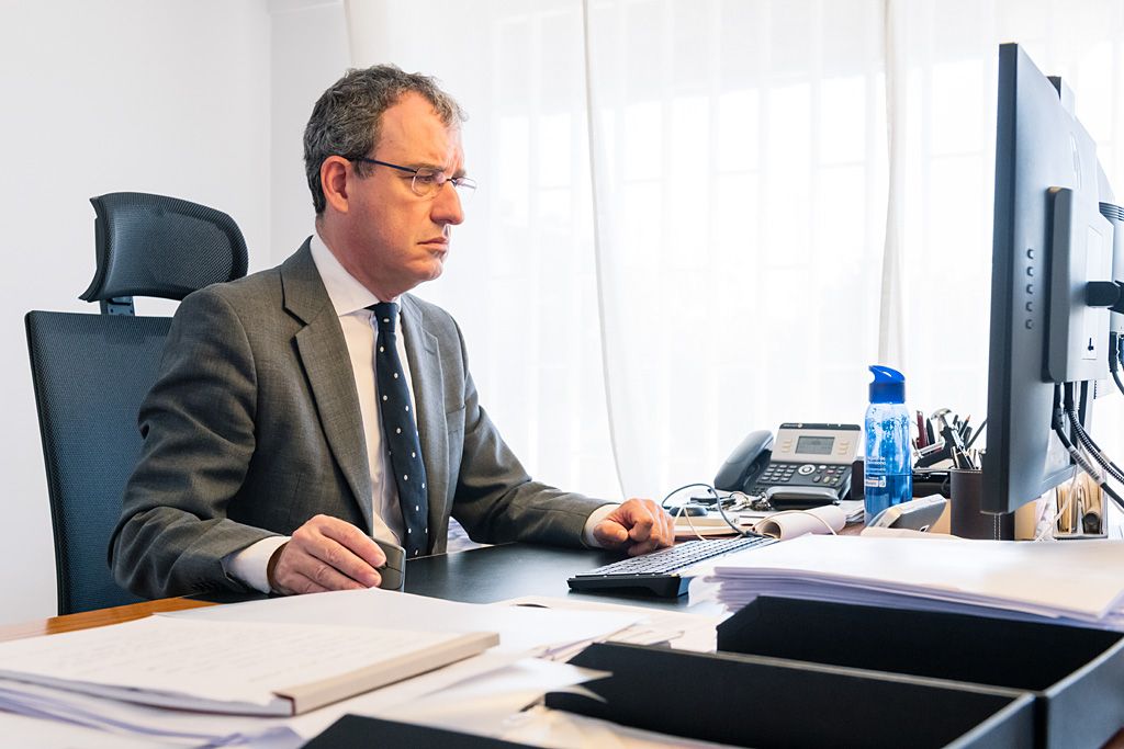 Profesional trabajando en un despacho laboralista con documentación y ordenador sobre la mesa.