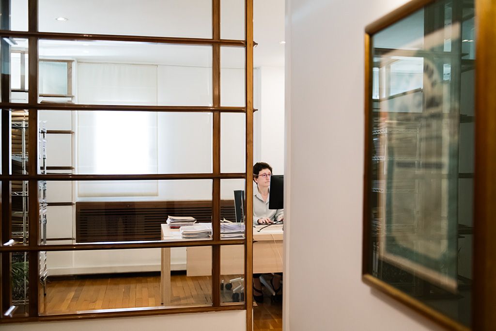 Vista de un espacio de trabajo en un despacho profesional con una persona trabajando al fondo.