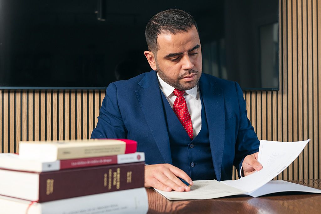 Profesional revisando documentación en un despacho de abogados con libros jurídicos en primer plano.