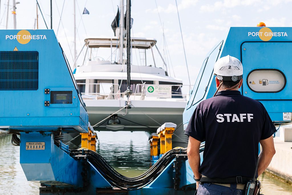 Trabajador de Port Ginesta junto a maquinaria náutica y una embarcación en el puerto.